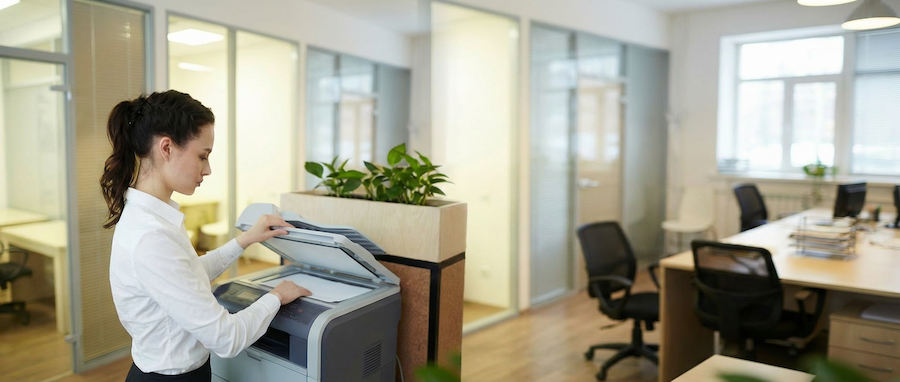 Woman using office printer copier in modern workplace